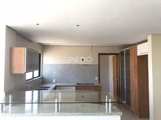 Vista da cozinha moderna com armários de madeira e bancada de granito.