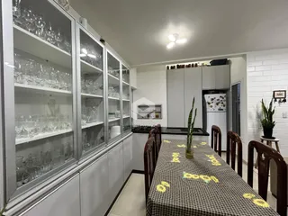 Vista de um ambiente interno com armários de vidro e mesa de jantar.