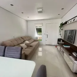 Uma sala de estar com um sofá grande e piso claro.