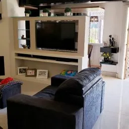 Uma sala de estar com sofá e televisão montada na parede.