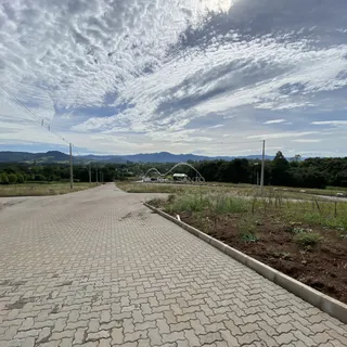 Vista da estrada pavimentada em uma área rural com colinas ao fundo.