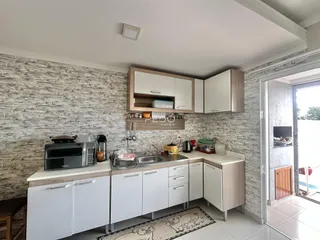 Cozinha moderna com armários brancos e parede de tijolos na Lajeado.