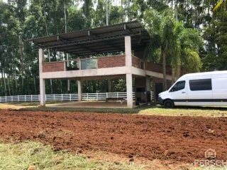 Vista externa de uma estrutura com pilares de concreto em um terreno com terra exposta.