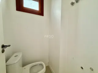 Vista de um corredor interno com um vaso sanitário branco.