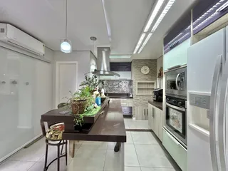 Vista interna de uma cozinha moderna com armários brancos e piso claro.