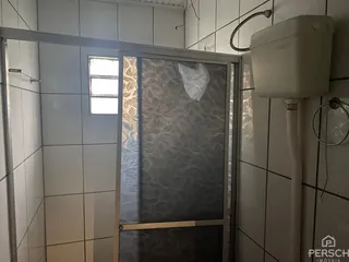 Foto de um banheiro com revestimento de azulejos brancos e box de vidro.