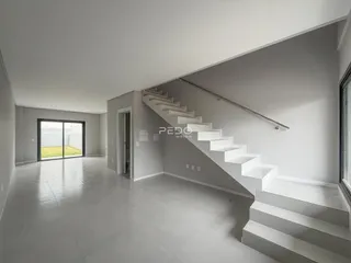 Interior de uma sala ampla com escadaria e piso de concreto polido.