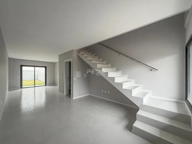 Interior de uma sala ampla com escadaria e piso de concreto polido.