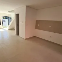 Hall de entrada com piso claro e paredes brancas.