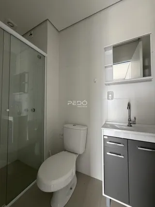 Foto interna de um banheiro moderno com box de vidro e bancada.