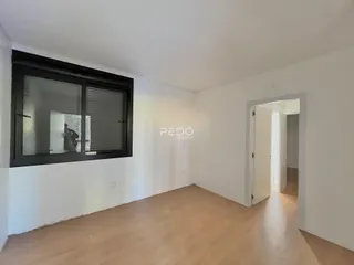 Interior de uma sala com piso de madeira e janela.