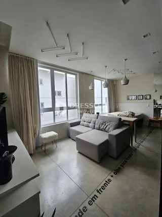 Sala de estar com grande janela e sofá claro em um imóvel no Brasil.