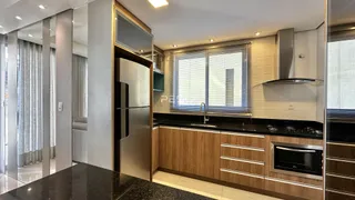 Vista da cozinha moderna com armários de madeira e eletrodomésticos de aço inoxidável.