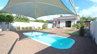 Foto de uma piscina externa em um pátio com grama e um guarda-sol.