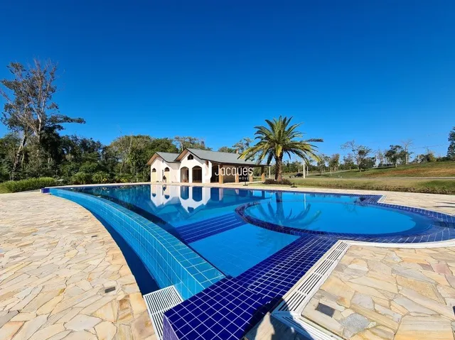 Vista externa de uma piscina cercada por pedras em uma propriedade no Brasil.