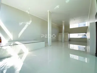 Interior de uma sala ampla com piso claro e paredes brancas.