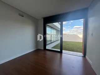 Uma sala de estar com piso de madeira e porta de vidro abrindo para o jardim.