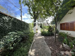 Vista externa de uma propriedade com jardim e calçada de tijolos.