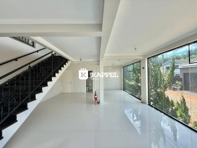 Foto de um hall amplo e iluminado com piso claro e grandes janelas.