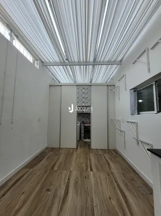 Um corredor interno com piso de madeira e teto de claraboia.