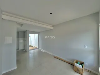 Ambiente interno amplo com piso de cerâmica e paredes claras de uma residência.