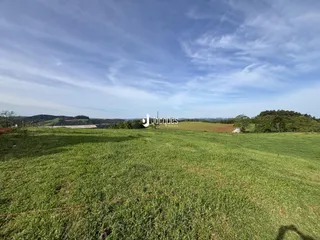 Campo verde aberto com paisagem rural ao fundo.