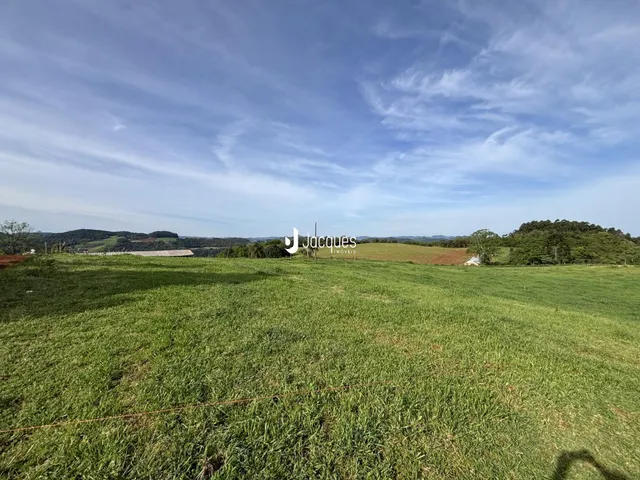 Campo verde aberto com paisagem rural ao fundo.