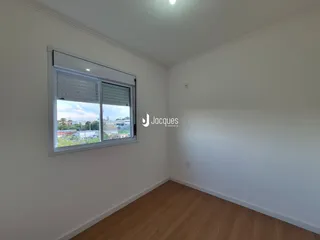 Vista interna de um cômodo com piso de madeira e janela.