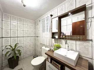 Banheiro com revestimento de azulejos brancos e bancada de madeira