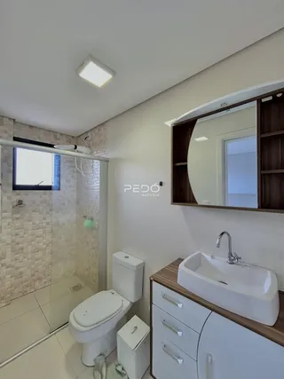 Foto de um banheiro com box de vidro e bancada de pia.