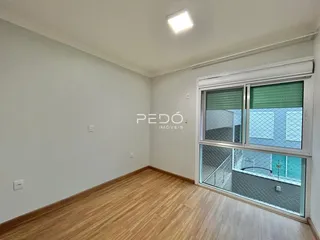 Ambiente interno de uma sala com piso de madeira clara e paredes brancas.