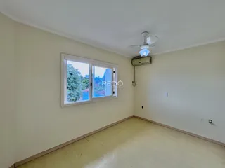 Quarto interno com piso de madeira e janela com vista para a paisagem.