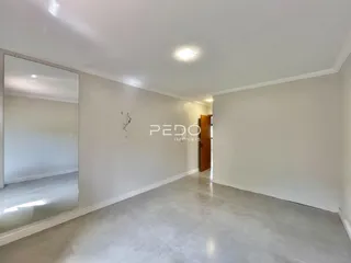 Hall de entrada com paredes brancas e piso claro.