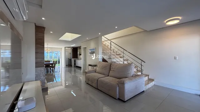 Sala de estar ampla com piso de porcelanato e sofá claro.