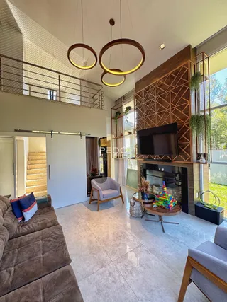 Sala de estar com pé direito alto e acesso a um corredor superior.