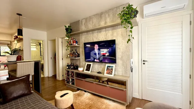 Sala de estar com decoração moderna e televisão montada na parede.