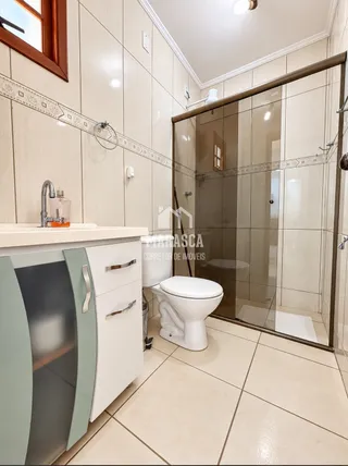 Foto de um banheiro moderno com box de vidro e vaso sanitário branco.