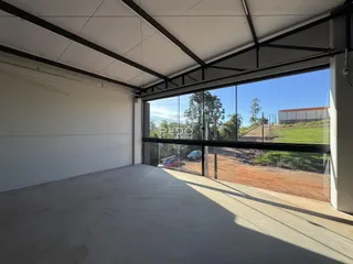 Interior de um espaço com piso de concreto e grande abertura para o exterior.