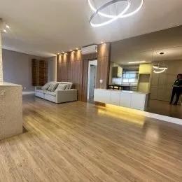 Sala de estar com piso de madeira clara e iluminação moderna.