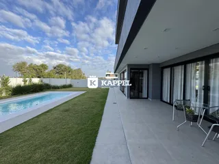 Vista externa de uma casa moderna com piscina e jardim.
