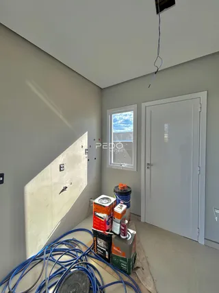 Interior de um cômodo com parede de gesso exposta e materiais de construção no chão.