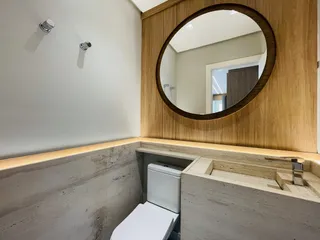 Banheiro com revestimento de pedra e bancada de madeira.
