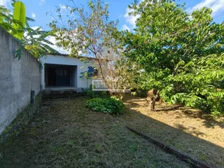 Vista da fachada de uma residência com jardim e vegetação ao redor.