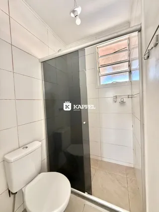 Foto interna de um banheiro com revestimento de azulejos brancos.
