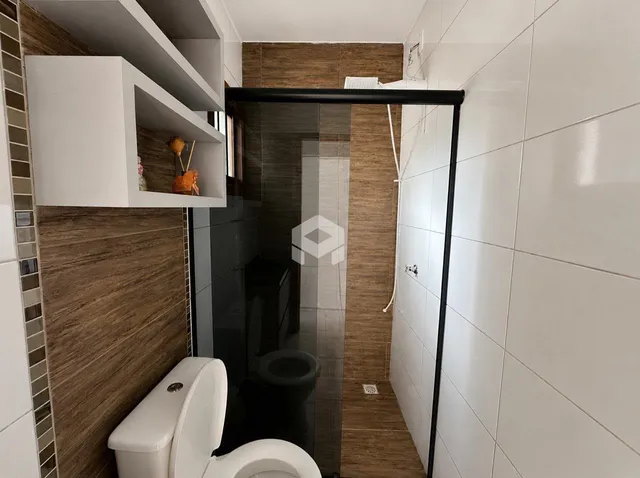 Foto de um banheiro com revestimento cerâmico e box de vidro.