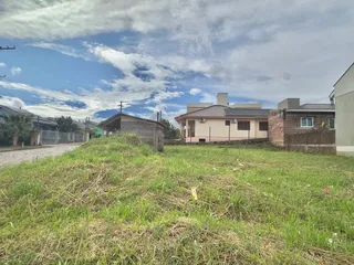 Vista externa de uma propriedade com gramado em primeiro plano e edifícios residenciais ao fundo.
