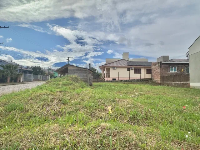 Vista externa de uma propriedade com gramado em primeiro plano e edifícios residenciais ao fundo.