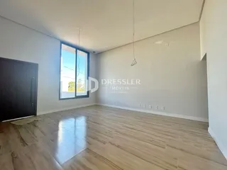 Sala de estar com piso de madeira clara e grande janela.