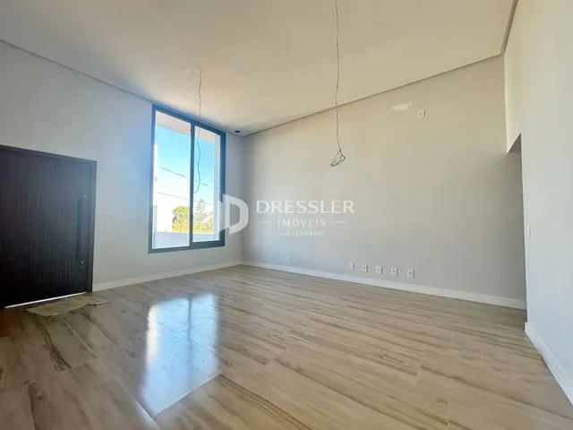 Sala de estar com piso de madeira clara e grande janela.