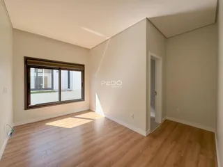 Ambiente interno de uma sala com piso de madeira e janela.